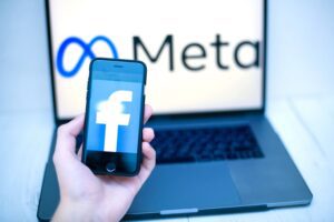 ręka trzymająca smartfon z logo Facebooka