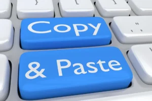 Zbliżenie na klawiaturę komputera z dwoma niebieskimi przyciskami z napisami Copy i Paste, symbolizujące kopiowanie treści ofert konkurencji.
