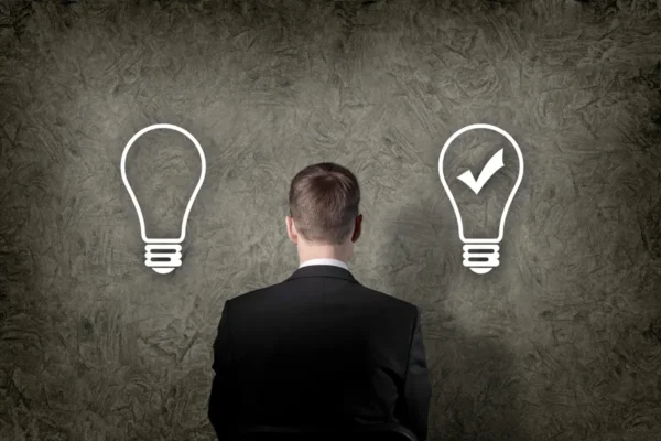 mężczyzna stojący tyłem przed ścianą z dwoma żarówkami symbolizującymi wybór między dwiema opcjami prawnymi