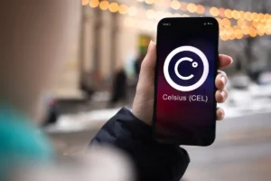 Dłoń trzyma smartfon z włączonym ekranem i logo Celsius CEL na tle rozmytych świateł miejskich. Nękające telefony z nieznanego numeru.